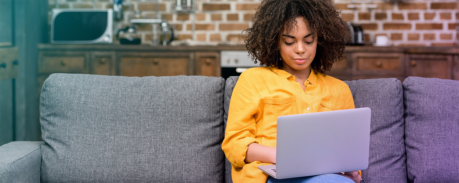 Young Black woman on couch with laptop