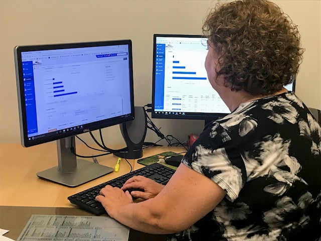 The image shows a woman working on a computer