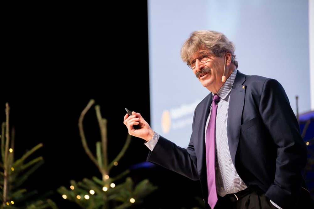 Gary Ruvkun delivering his Nobel Lecture in Stockholm wearing a dark shirt and purple necktie