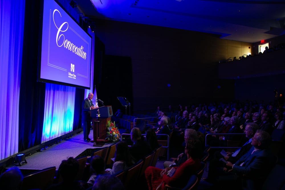  Photo of UMass Chan Chancellor Michael F. Collins addressing a crowd from a podium on a stage at the 2024 Convocation ceremony. 