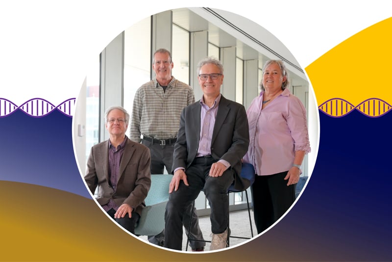 A photo of RNA Therapeutics Institute founders Phil Zamore, Craig Mello, Victor Ambros and Melissa Moore. They are standing in a hallway in the Paul J. DiMare Center. Zamore and Ambors are seated in the foreground, with Mello and Moore standing behind them. 