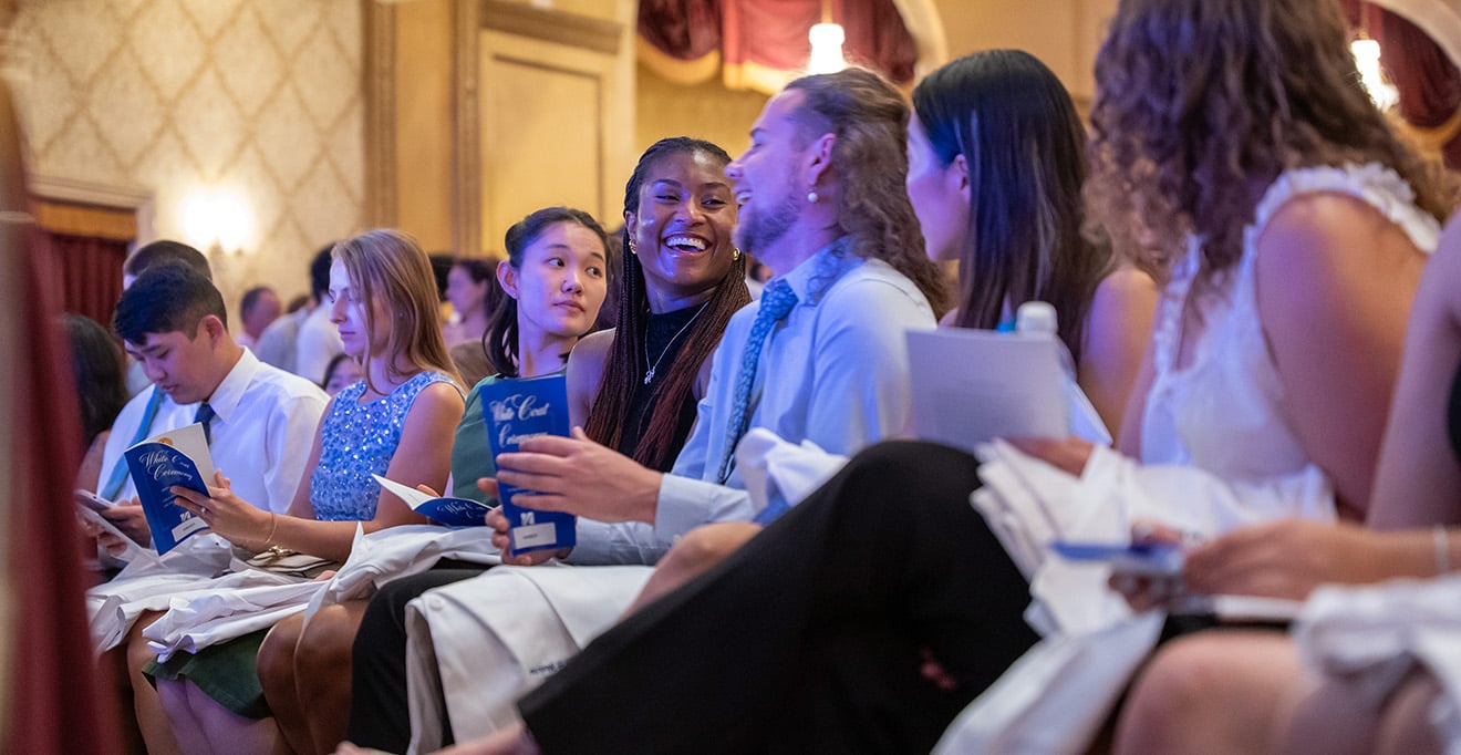 Students share a laugh at the start of the White Coat Ceremony for the T.H. Chan School of Medicine Class of 2029.